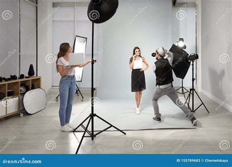 Professional With Assistant Taking Picture Of Young Woman In Modern