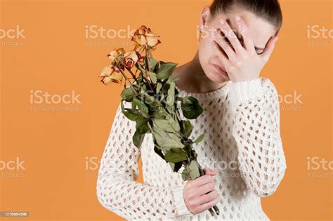 Girl Covers Her Face In Crying She Holds Withered Flowers In Her Hands