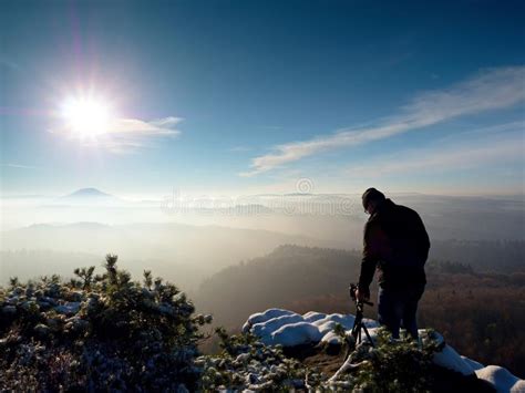 Man Takes Photos With Camera On Sharp Rock Dreamy Fogy Landscape Stock