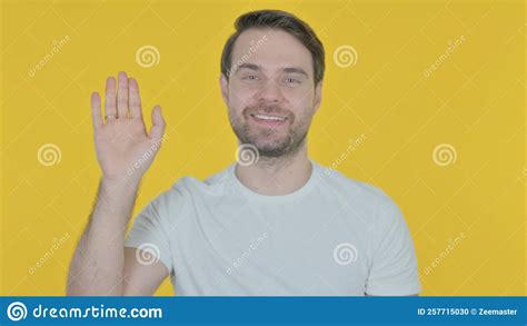 Young Man Waving Hand To Say Hello On Yellow Background Stock Photo