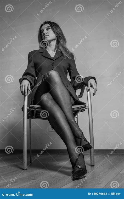 Young Charming Girl Sitting On A Chair In A Jacket Pantyhose And Shoes