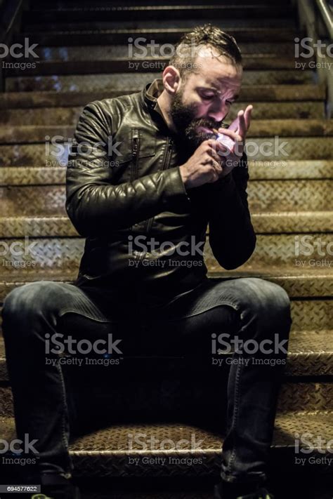A Portrait Of A Tough Bearded Man Lighting A Cigarette In The Streets