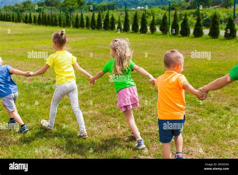 Children Holding Hands And Play On The Green Lawn Stock Photo Alamy