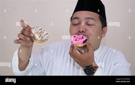 Portraits Of Overweight Or Fat Asian Muslim Men Enjoy Eating Two Donuts