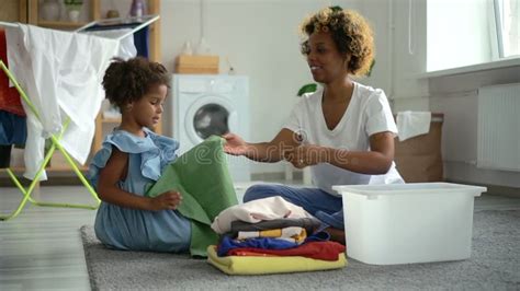 Mom And Daughter Do Household Chores And Have Fun Sits In Home Laundry