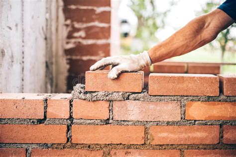 Bricklayer Worker Placing Bricks On Cement While Building Exterior