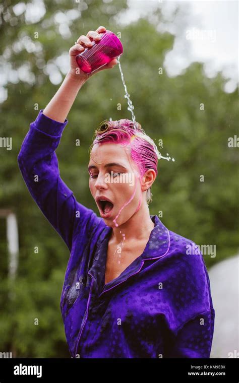 Woman With Pink Hair Pouring A Glass Of Water Over Her Head Stock Photo