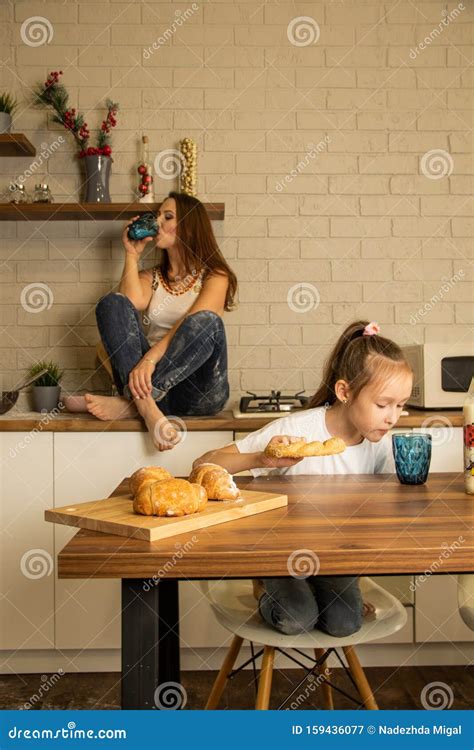 MamÃ¡ E Hija En La Cocina Come Bollos Con Leche Imagen De Archivo