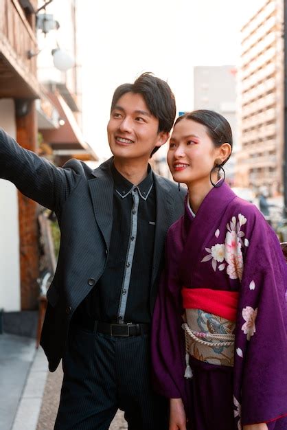 Японская пара отмечает день совершеннолетия на открытом воздухе делая селфи Бесплатно Фото