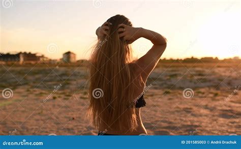 Woman In Bikini Swimsuit Ruffles Her Long Hair Against Setting Sun On