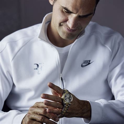A Man In A White Jacket Is Holding His Watch And Looking Down At The Wrist