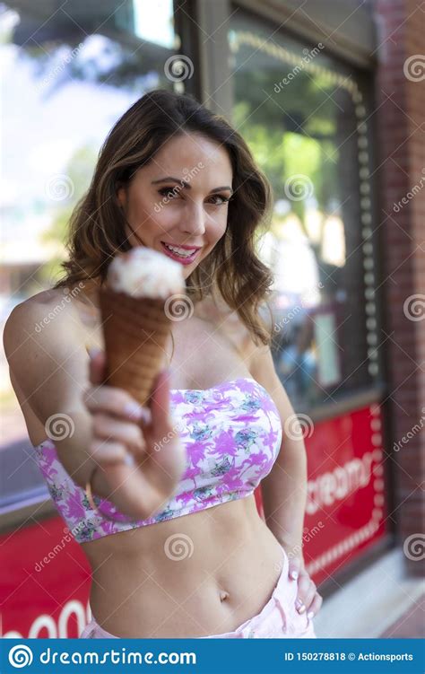 Lovely Brunette Model Eats Ice Cream Outside An Ice Cream Store Stock