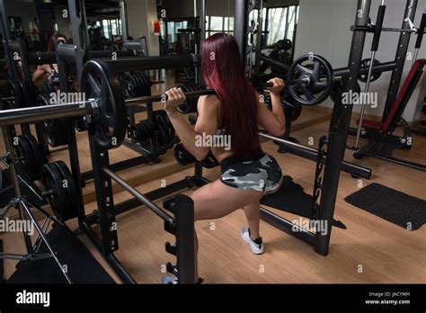 Young Woman Working Out Legs With Barbell In A Gym Squat Exercise