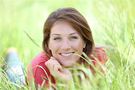 retrato da mulher de sorriso que encontra se na grama que sente relaxado imagem de stock