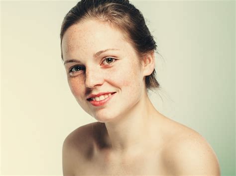 裸の肩の美しいそばかすの女性の顔の肖像画は若い。青い背景。 プレミアム写真