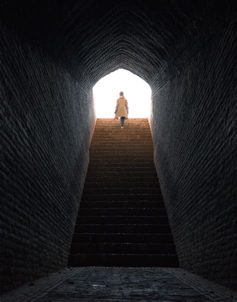 Lone Woman Walks Up Stairs Coming Out From Dark Tunnel Into Bright