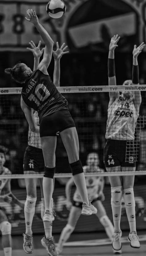 Two Women Are Playing Volleyball In Black And White While One Woman Jumps Up To Hit The Ball