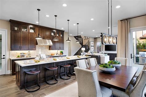 A breakfast bar is either a full kitchen island or a countertop overhang with a height that has enough room for the legs and a size that can accommodate ample room for meals. Contemporary pendant lighting & eye-catching chandelier | Spencer model home kitchen | Irvine ...