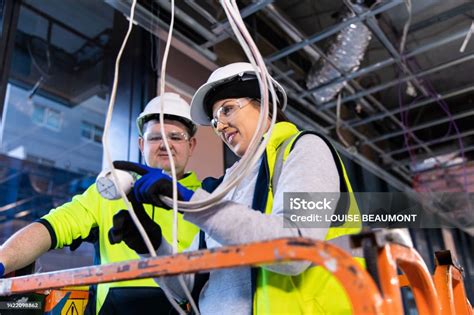 Real Life Female Electrician And Her Coworker At Work Stock Photo