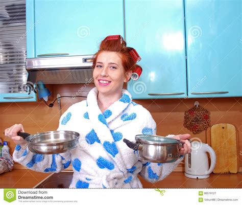 The Attractive Young Red Haired Housewife In A Dressing Gown And About Hair Curlers In Kitchen