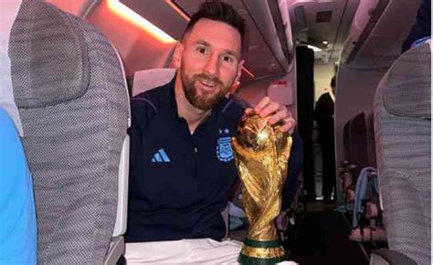 A caminho da Argentina Messi posa com taça da Copa do Mundo no avião