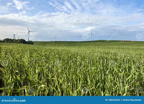 Wind Turbine On The Green Grass Over The Blue Clouded Sky Protection