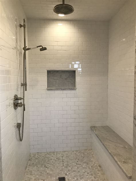 Walk into a large master bathroom shower to admire thin gray marble herringbone floor tiles and marble slab walls featuring stacked shower niches and a marble shower bench. Marble master bathroom walk-in shower (no lip, no curtain ...