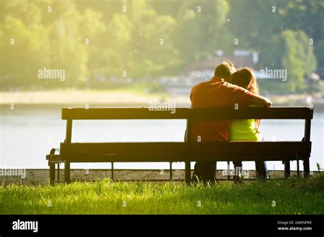 Rear View Of A Young Couple Sitting On A Park Bench Romantic