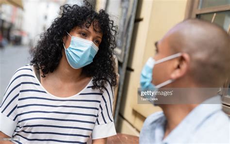 Couple Sitting In A Caffe Bar With Surgical Masks During The