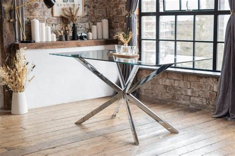 A Glass Table Sitting In Front Of A Window Next To A Brick Wall And Wooden Floor
