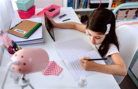 Niña Estudiando En Casa Con Tablet Y Máscara En La Mesa Imagen De