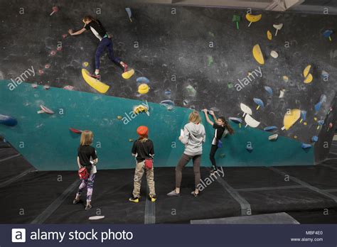 Female Instructor And Rock Climbing Students Watching Girl Climbing