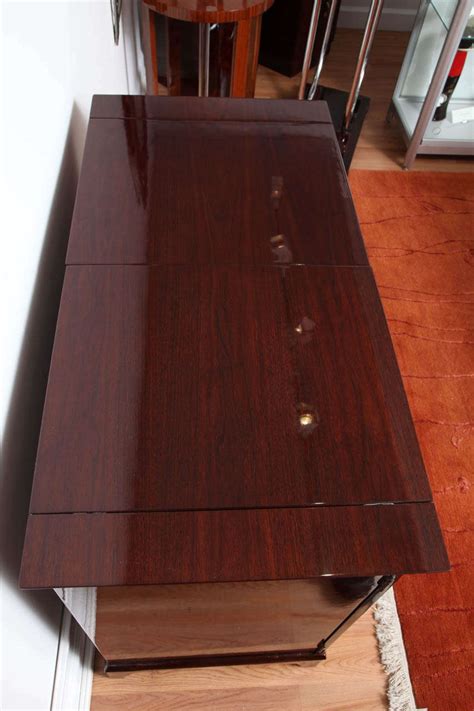 Once opened, this handsome bar features a hidden drawer, numerous shelves, wine racks, glass storage, and about anything else regarding bar storage. Mid-Century Fold-Out Bar Cabinet For Sale at 1stdibs