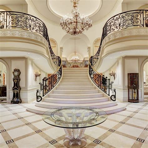 A Large Foyer With Marble Flooring And Chandelier On The Second Story