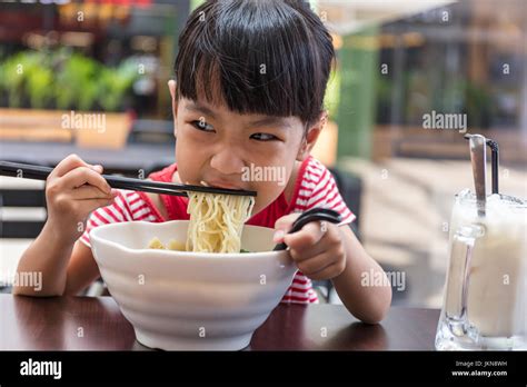 Asian Little Chinese Girl Eating Noodles Soup In Outdoor Cafe Stock