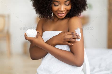 Beautiful Black Lady Wearing Towel After Bath Applying Cream Rubbing In Nourishing Body Butter