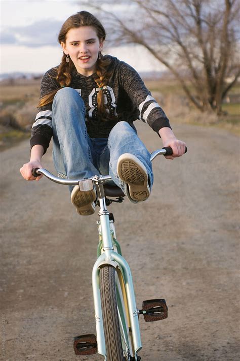 A Young Teen Girl Rides Bike With Feet On Handle Bars By Stocksy