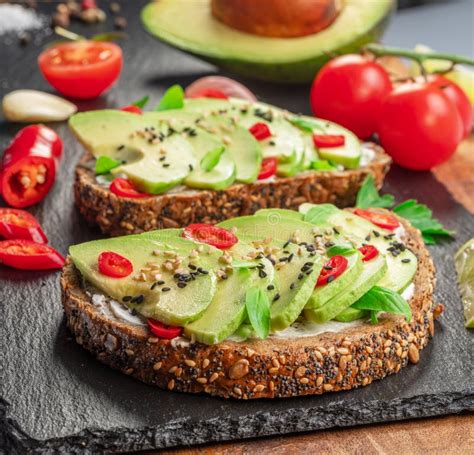 Avocado Toasts Bread With Avocado Slices Pieces Of Red Pepper And Sesame On Black Stone Board