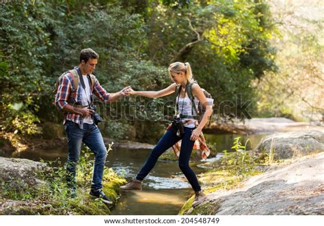 Young Man Helping Girlfriend Crossing Stream Stock Photo 204548749