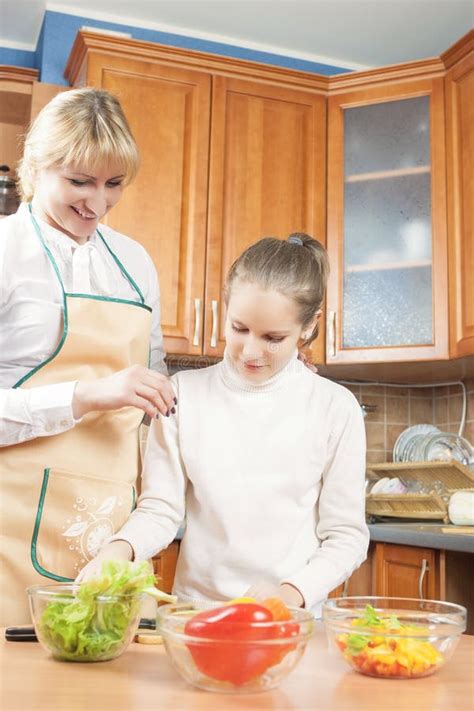 Mother Teaching Her Teenage Daughter To Cook Salad In The Kitch Stock