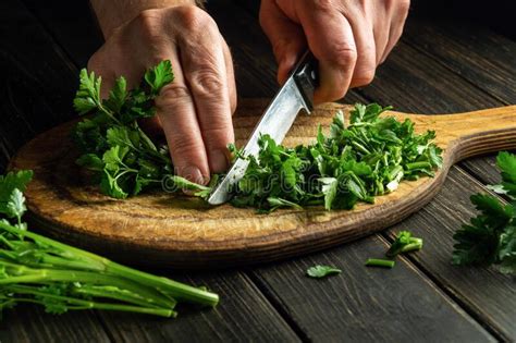 The Chef Cuts Green Parsley On A Cutting Board With A Knife For