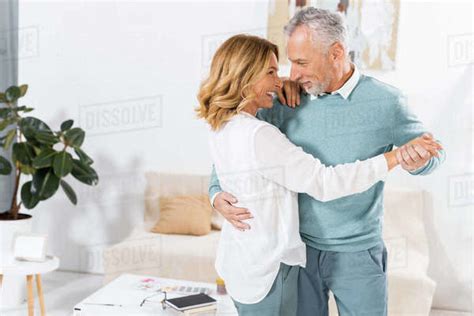 Couple Looking At Each Other While Dancing In Living Room At Home