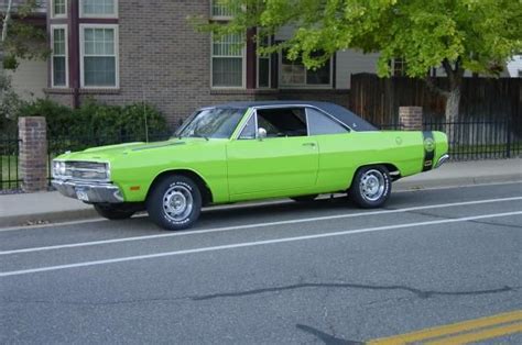 A Bright Green Car Parked On The Side Of The Road In Front Of A Brick