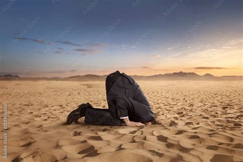 Desparate Businessman Hiding Head In The Sand At The Desert With Copy