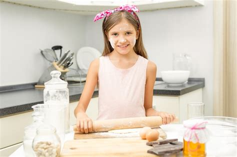 Premium Photo Smiling Girl Rolling Dough On Messy Kitchen