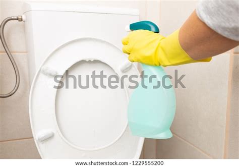 Person Spraying White Toilet Seat Reservoir Stock Photo 1229555200
