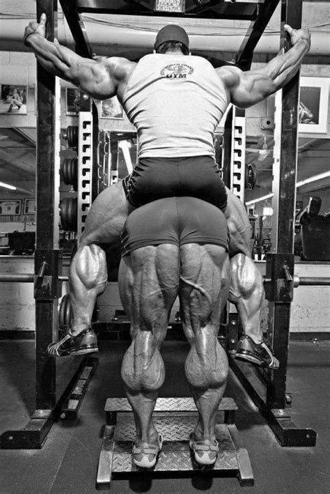 A Man Doing Squats On A Bench In A Gym With His Back Turned To The Camera