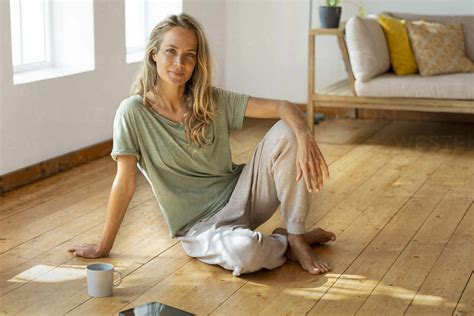 Relaxed Woman Sitting On Floor In Living Room Stock Photo