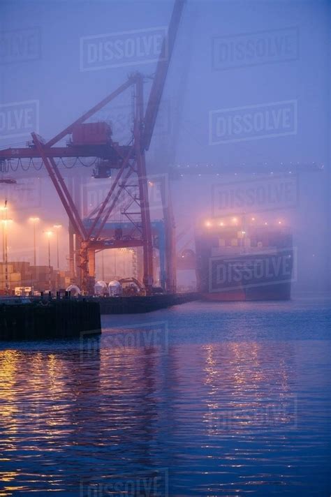 Misty View Of Cargo Ship And Cranes On Waterfront At Night Seattle