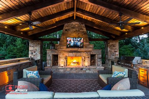 A Pavilion With An Outdoor Kitchen Fireplace And An Entertainment